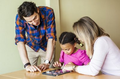 Teachers with girl painting on tablet
